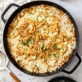 a black skillet with French onion casserole and french fried onions in a bowl.