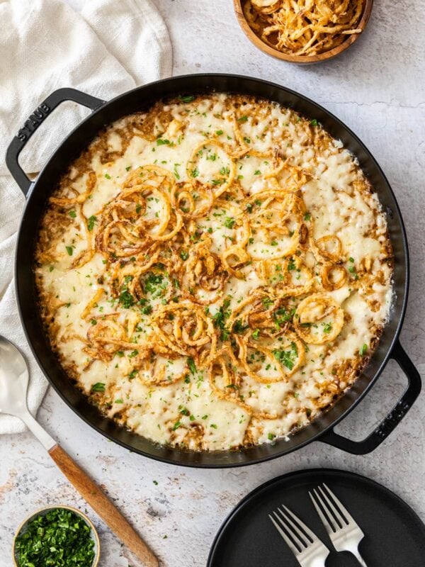 a black skillet with French onion casserole and french fried onions in a bowl.
