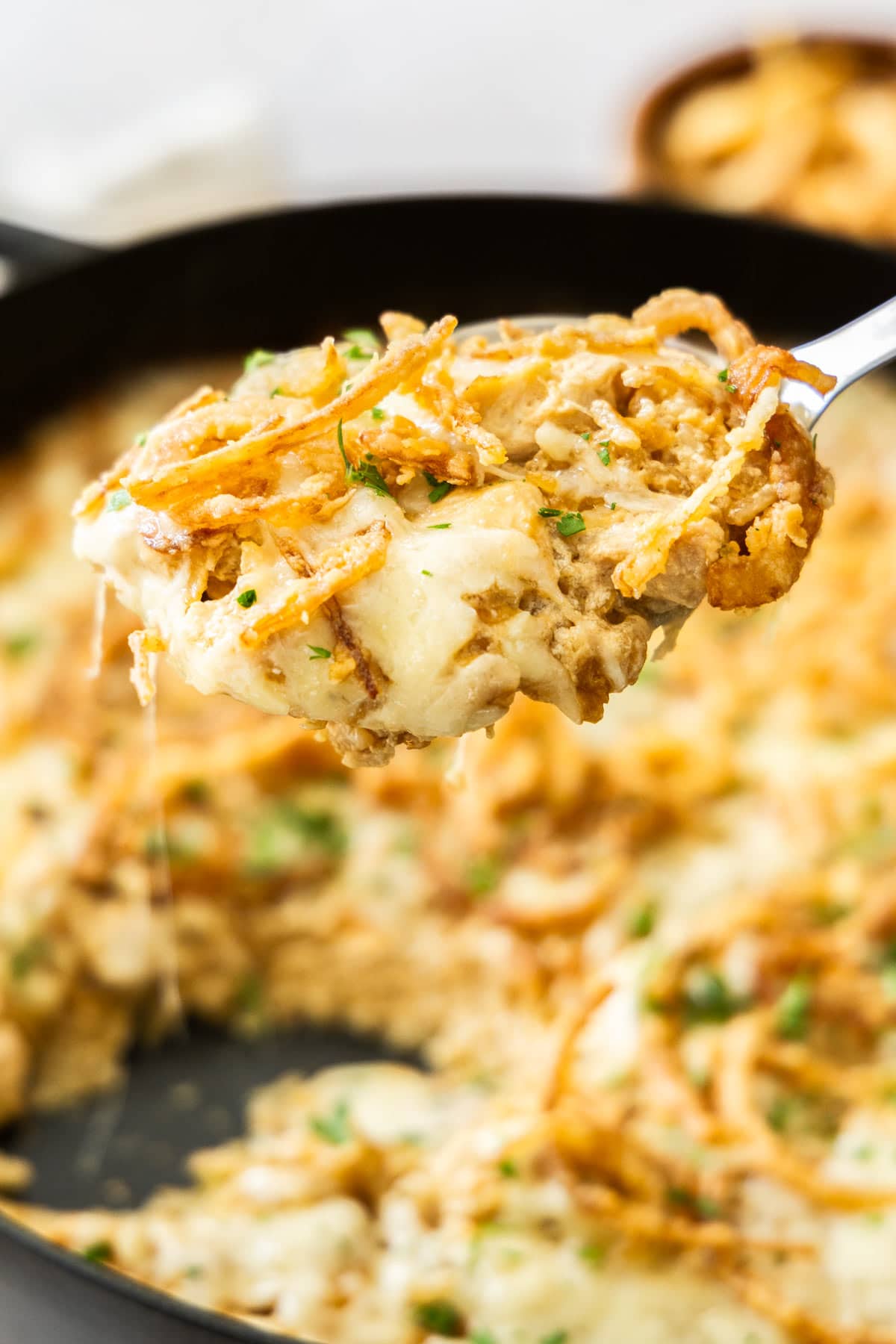 a spoonful of cheese and rice hovering over a black skillet.