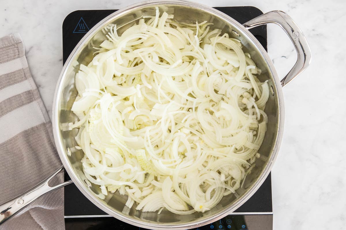 a stainless skillet with sliced onions.