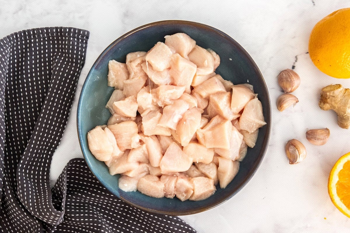 a green bowl of cubed raw chicken.