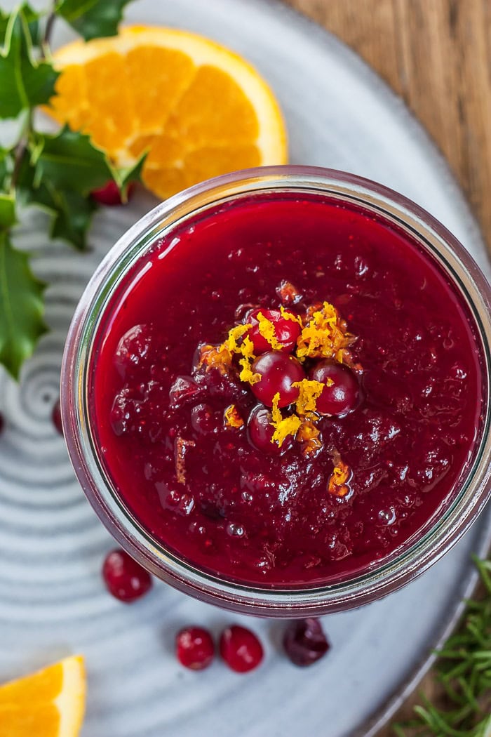a glass bowl of cranberry sauce topped with orange zest.