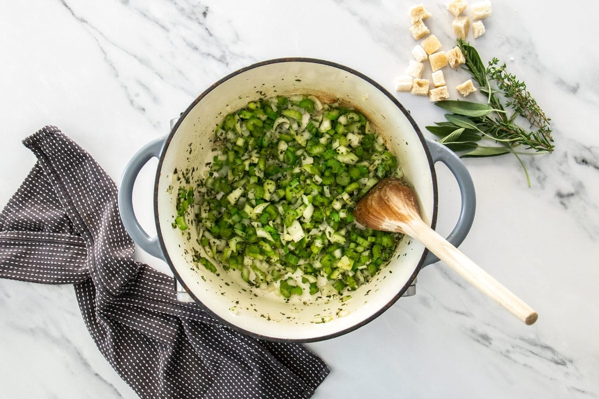 celery and herbs in a green Dutch oven.