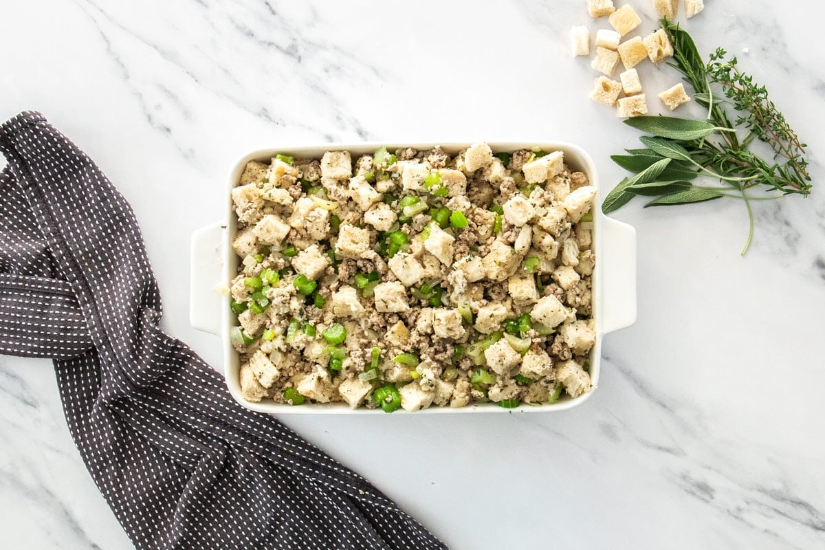a white casserole dish with unbaked sausage stuffing.