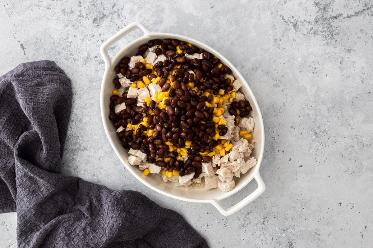 black beans, corn, and chopped turkey in a white baking dish.