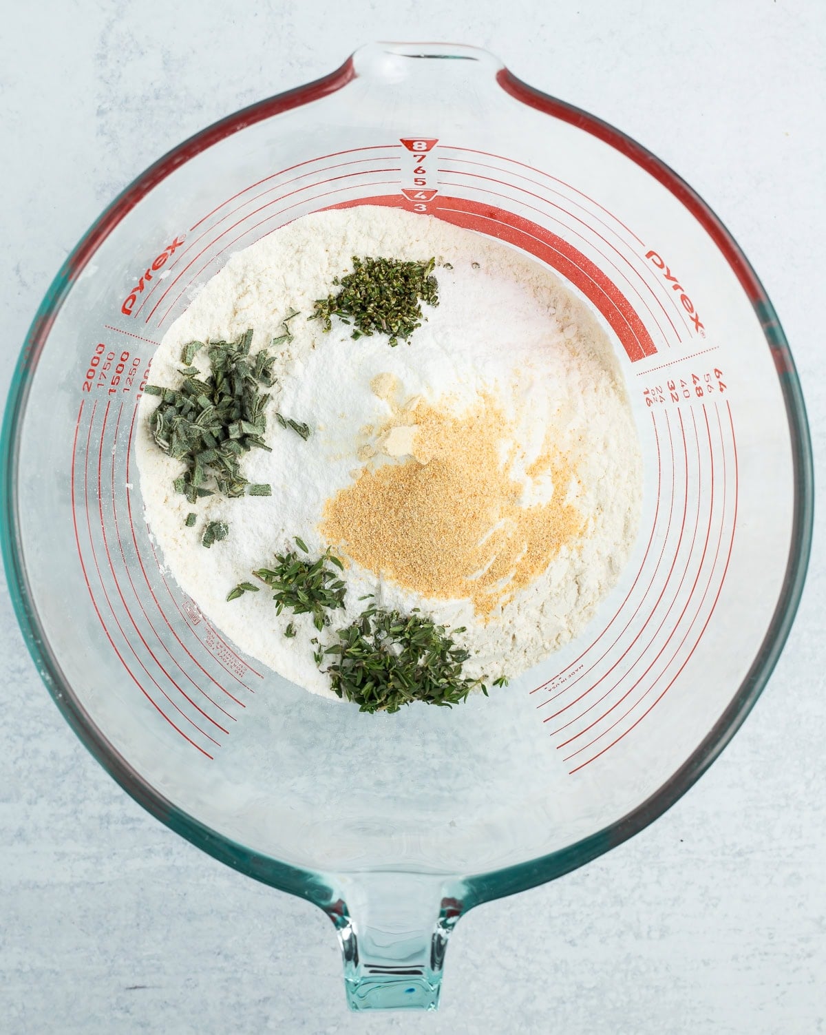 flour, herbs, and other ingredients in a glass bowl.