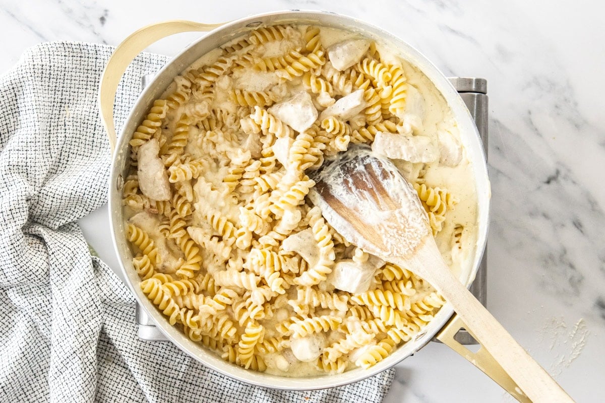 pasta, chicken, and a cream sauce in a skillet.