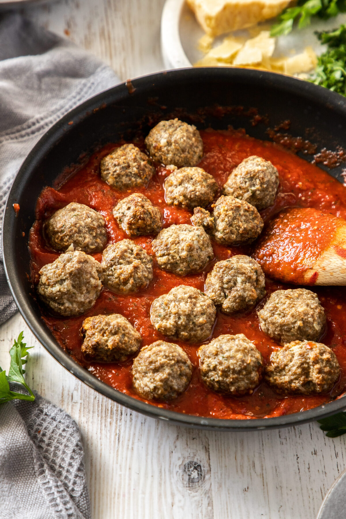 a skillet with red sauce and meatballs.