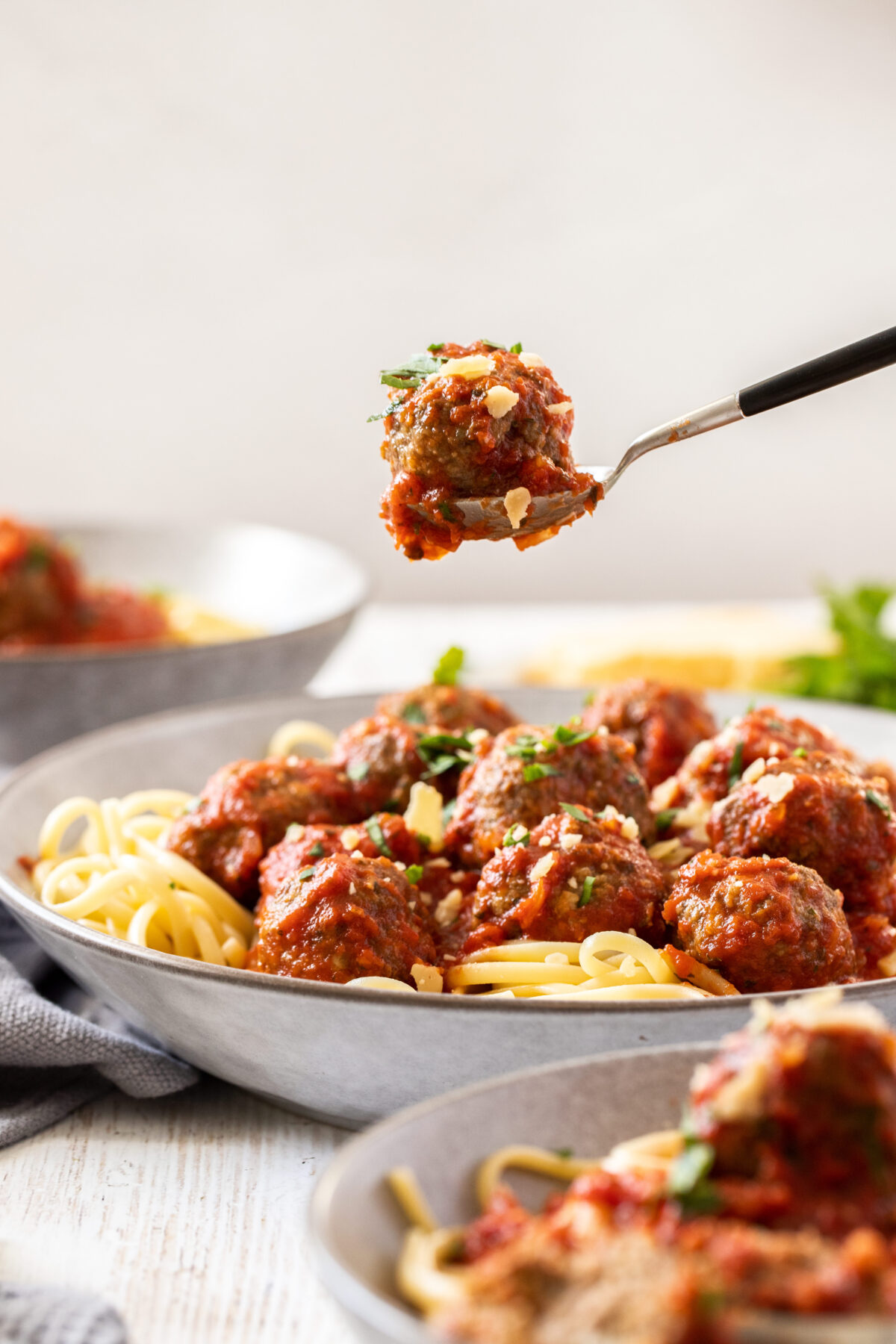 a spoonful hovering over a plate of pasta.