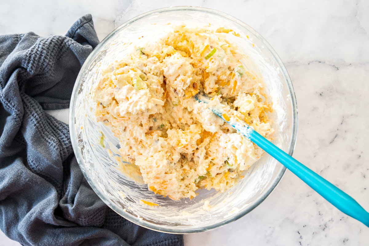 shredded potatoes and other ingredients mixed in a glass bowl.