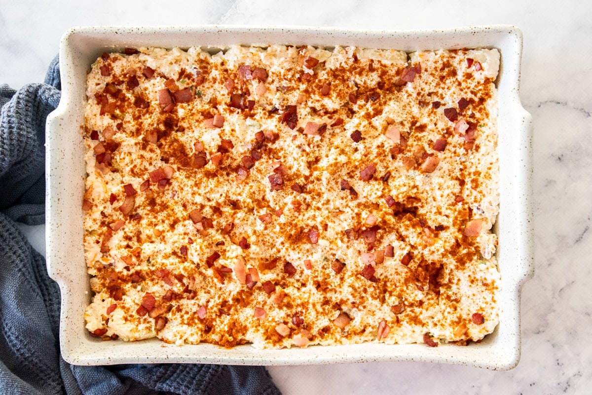unbaked shredded potato casserole in a white baking dish.