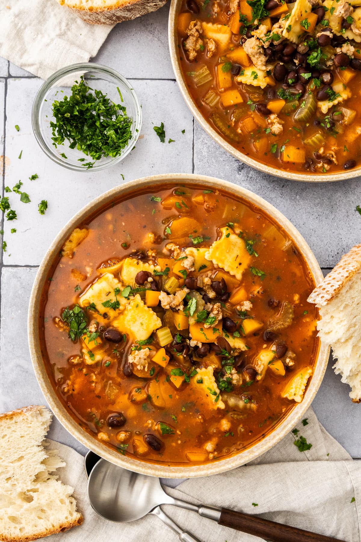 two bowls of soup on grey tiles.