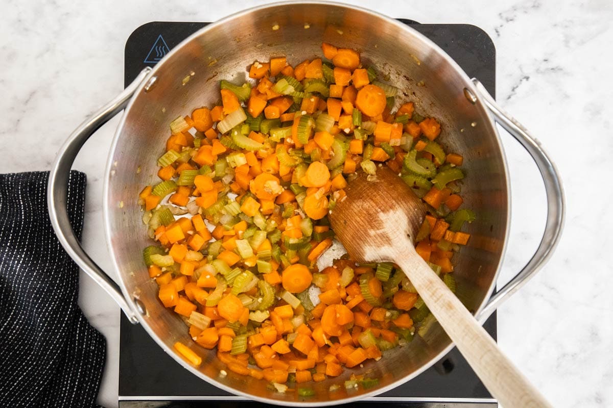 veggies being sauteed in a stainless pot.