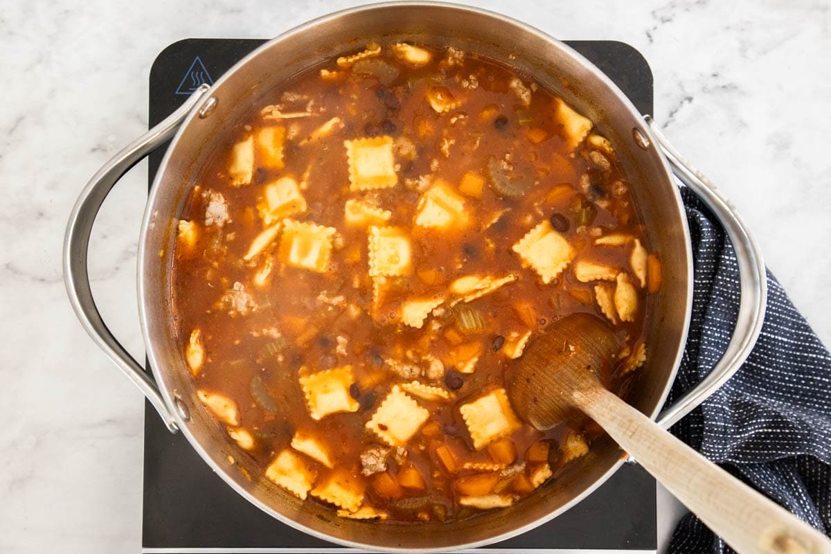 ravioli soup being cooked in a stainless pot.