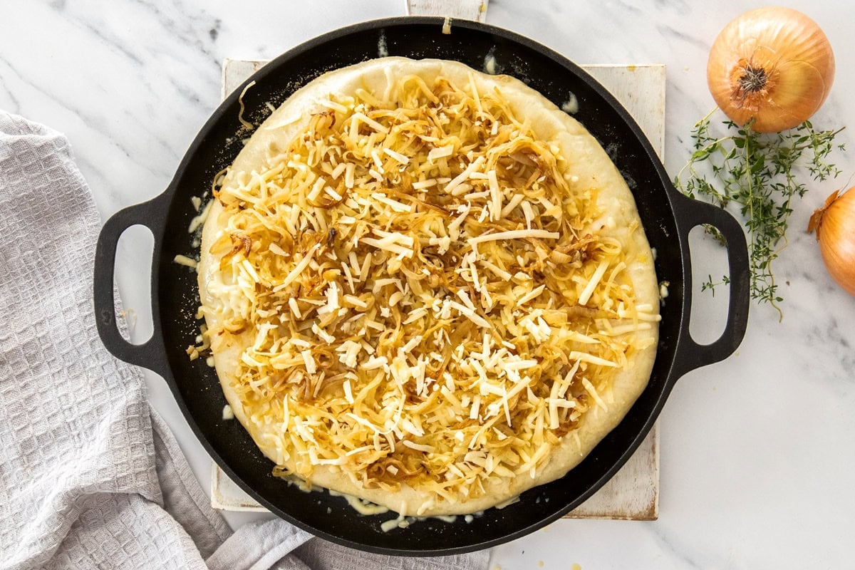 shredded cheese and other ingredients topping an unbaked pizza.
