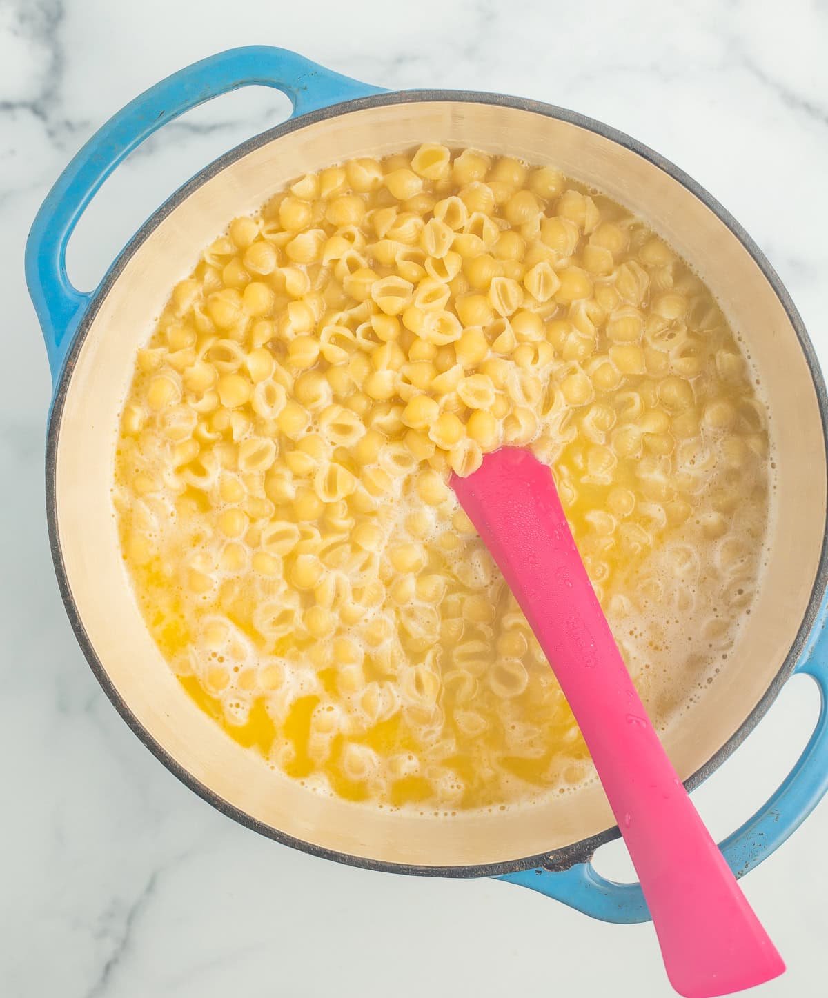 partially cooked noodles in a blue Dutch oven.