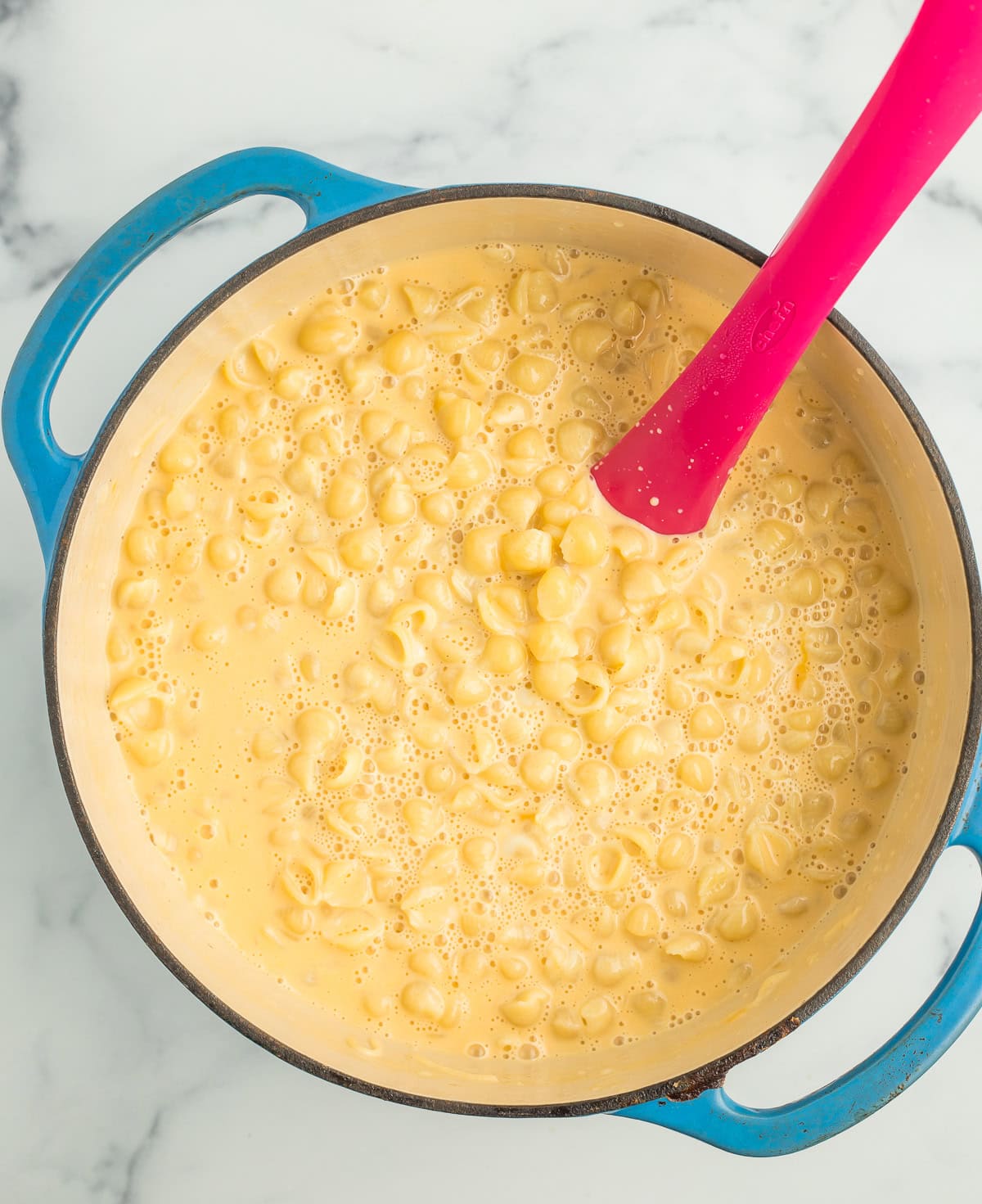 creamy mac and cheese in a blue Dutch oven.