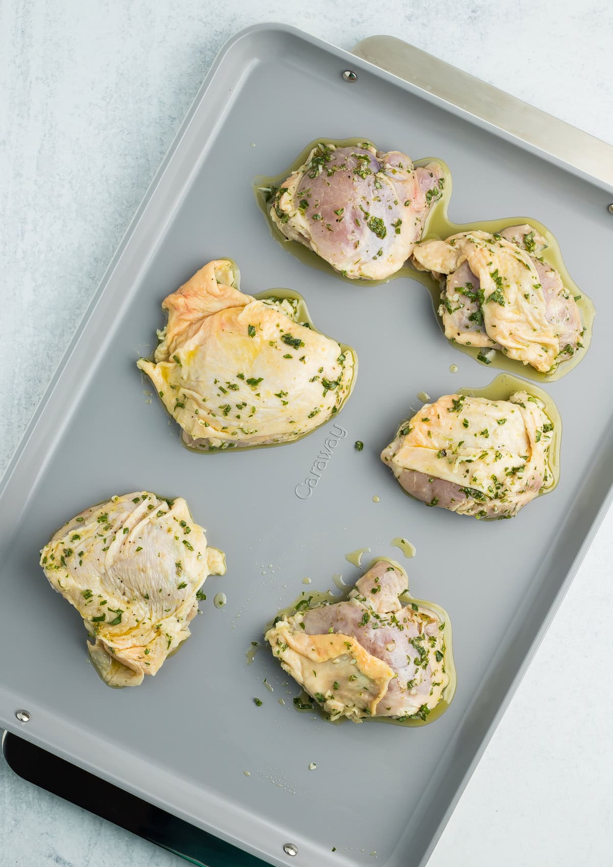 Unbaked chicken thighs on a sheet pan.