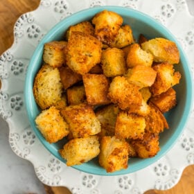 baked seasoned cubes of bread in a blue dish on a white dish.