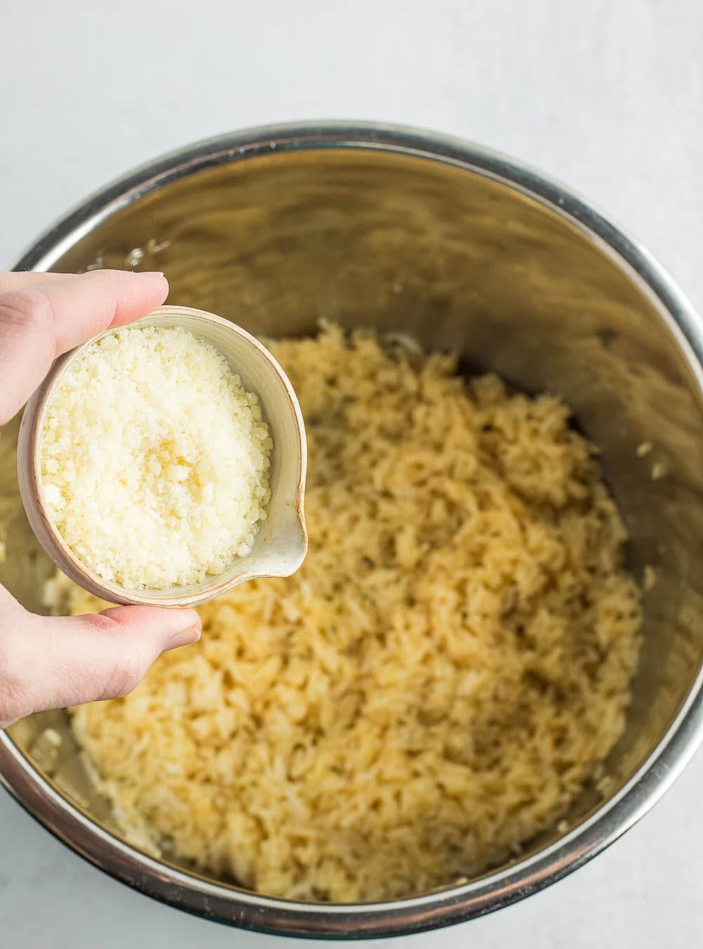a small dish of parmesan over rice in a stainless pot.