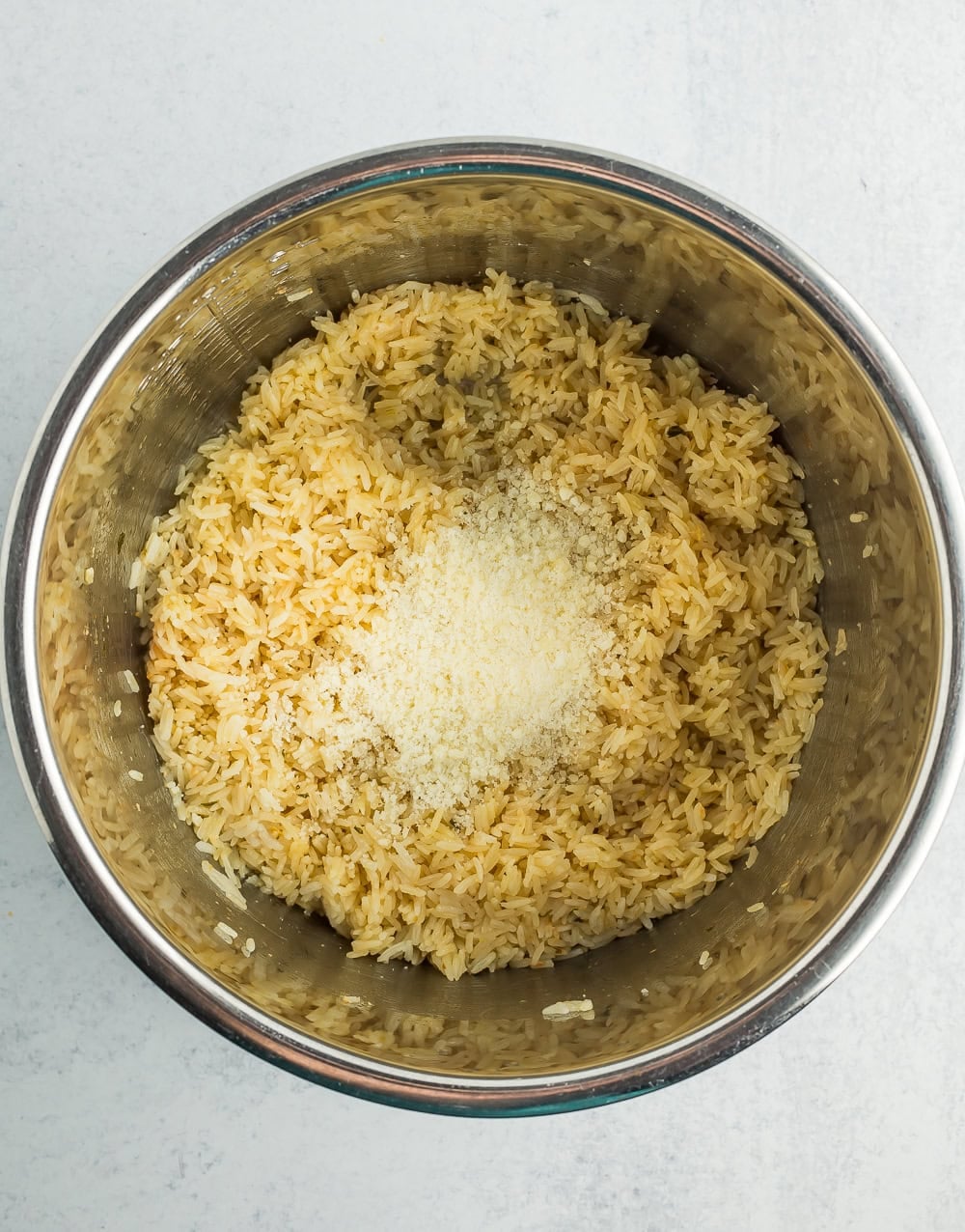 Parmesan on top of rice in a stainless pot.