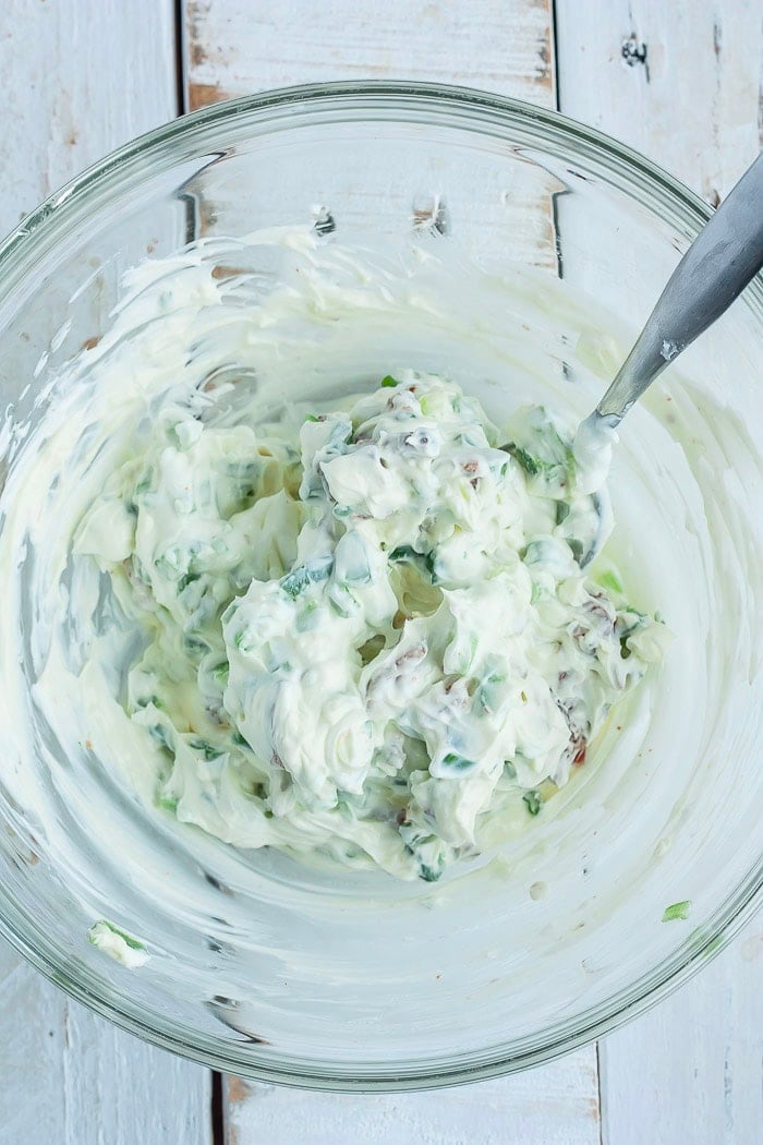 a cream cheese sauce in a glass bowl with a spoon.