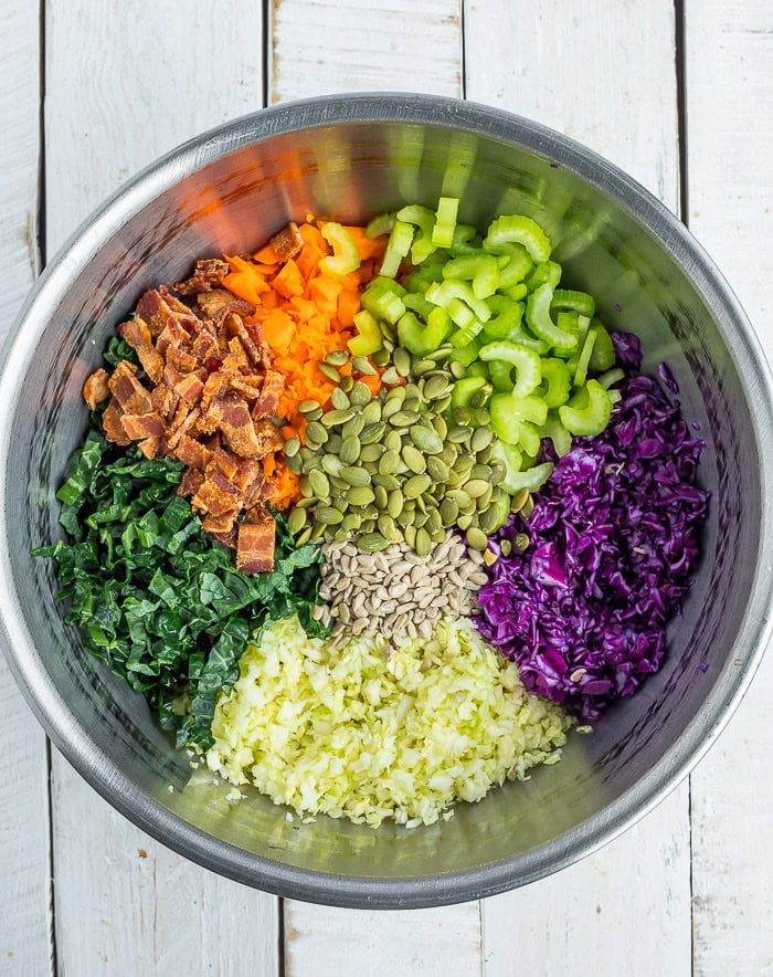 cabbage, celery, carrots, kale, and other ingredients in a large metal bowl.