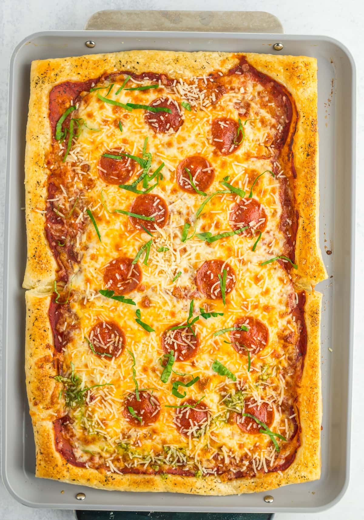 baked puff pastry pizza on a baking sheet topped with ribbons of basil.