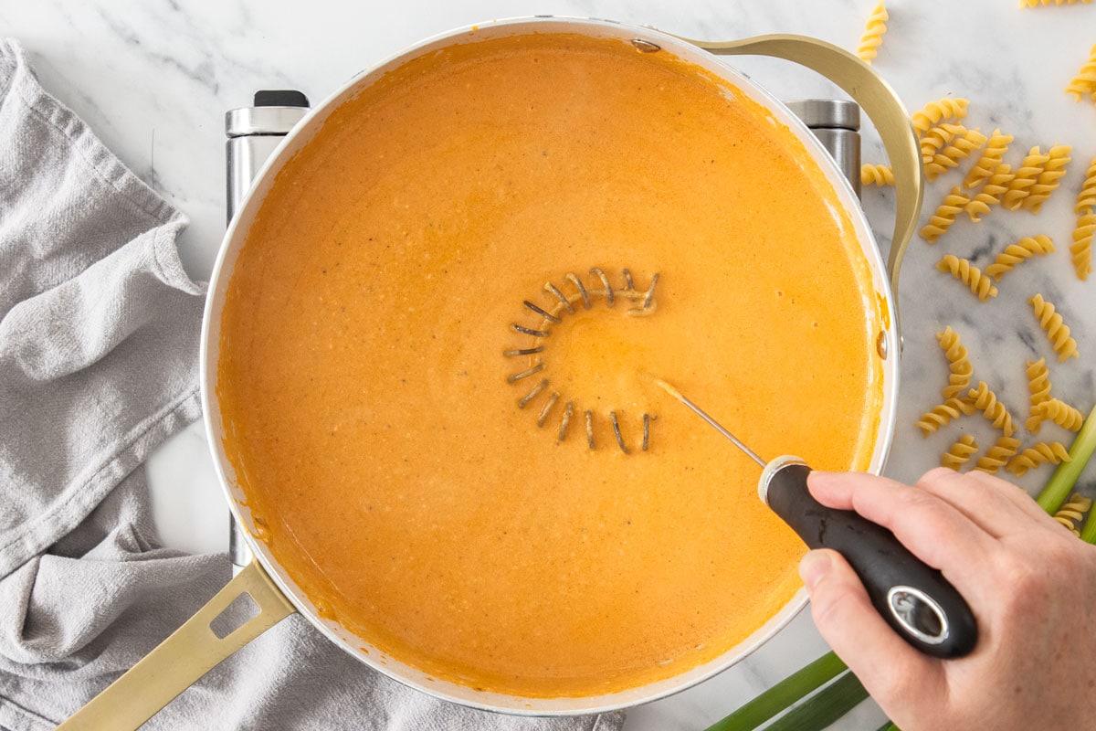 a creamy sauce being whisked in a skillet.
