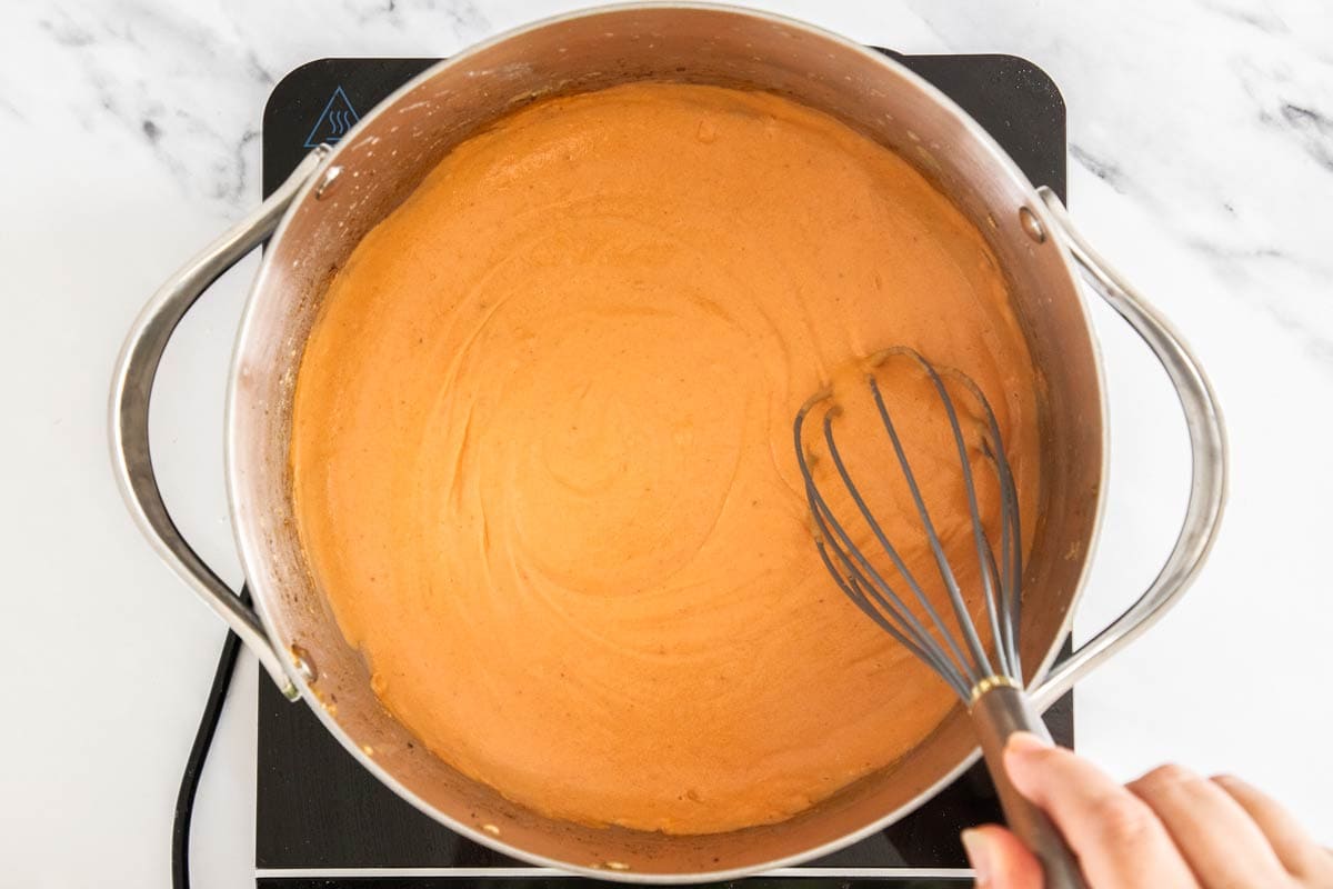 a creamy red sauce being made in a stockpot.