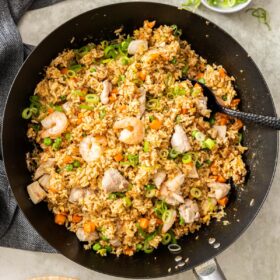 shrimp and chicken fried rice in a black wok.