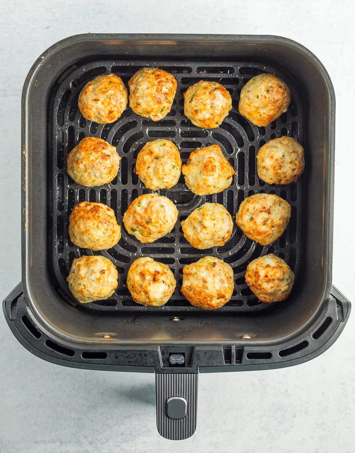 baked meatballs in an air fryer basket.
