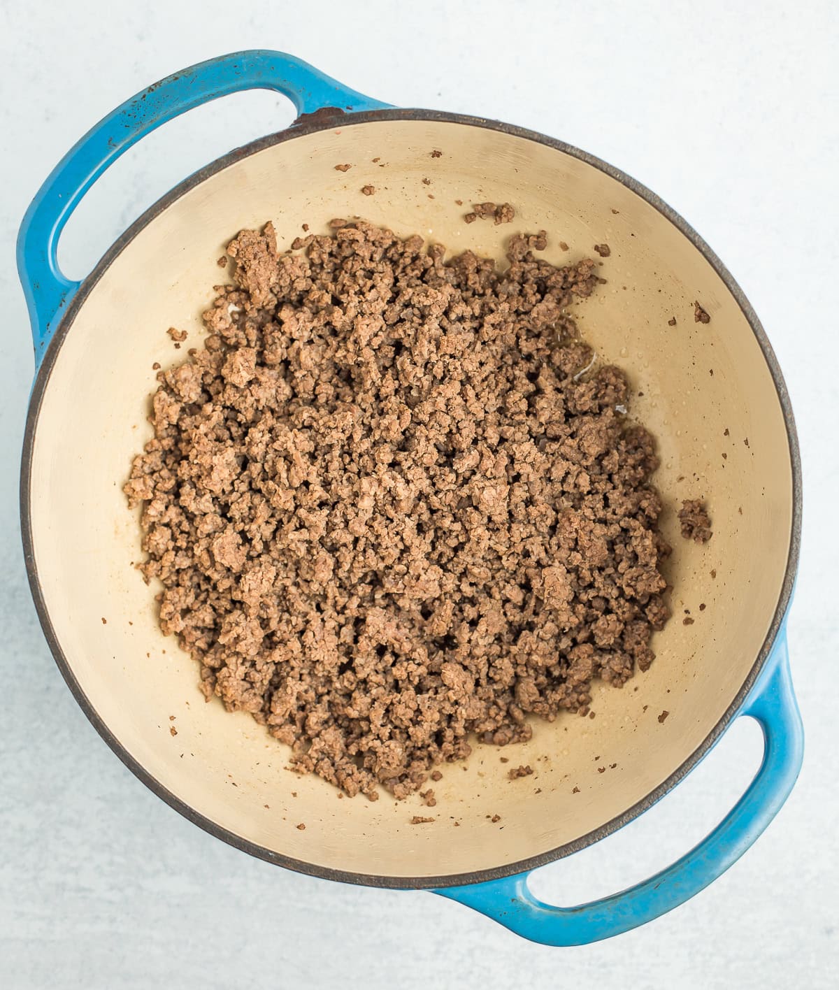 ground beef browned in a blue Dutch ovecn.