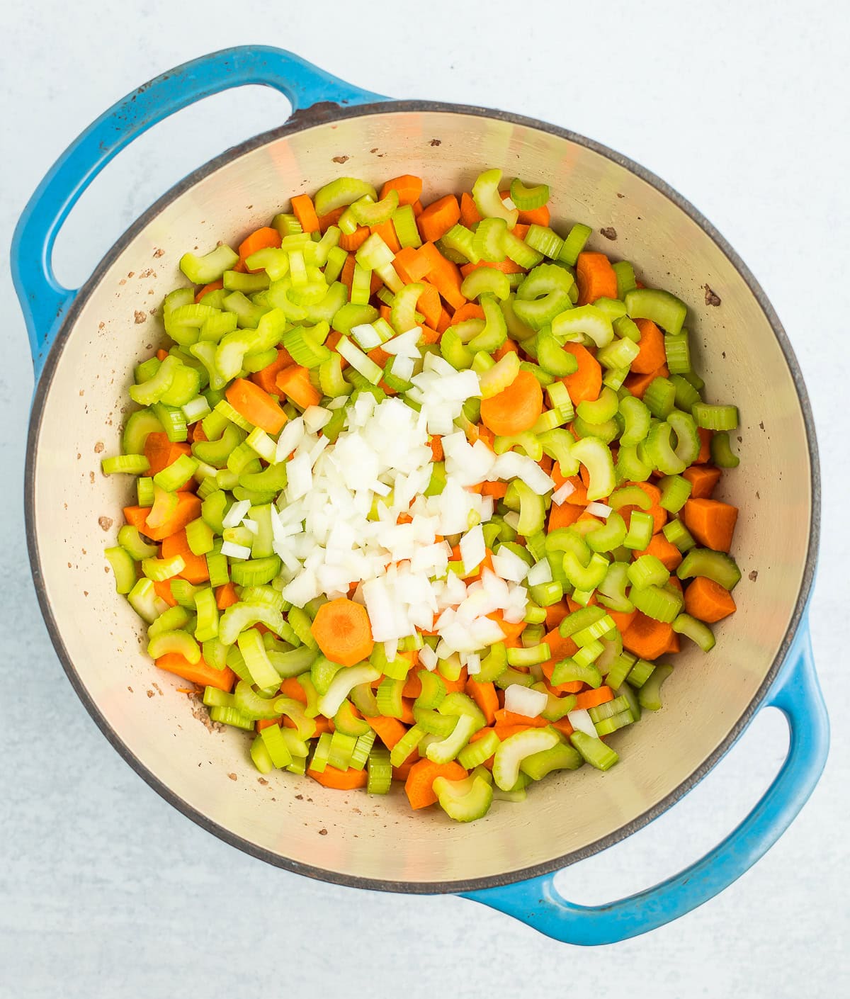 chopped veggies in a blue Dutch oven.