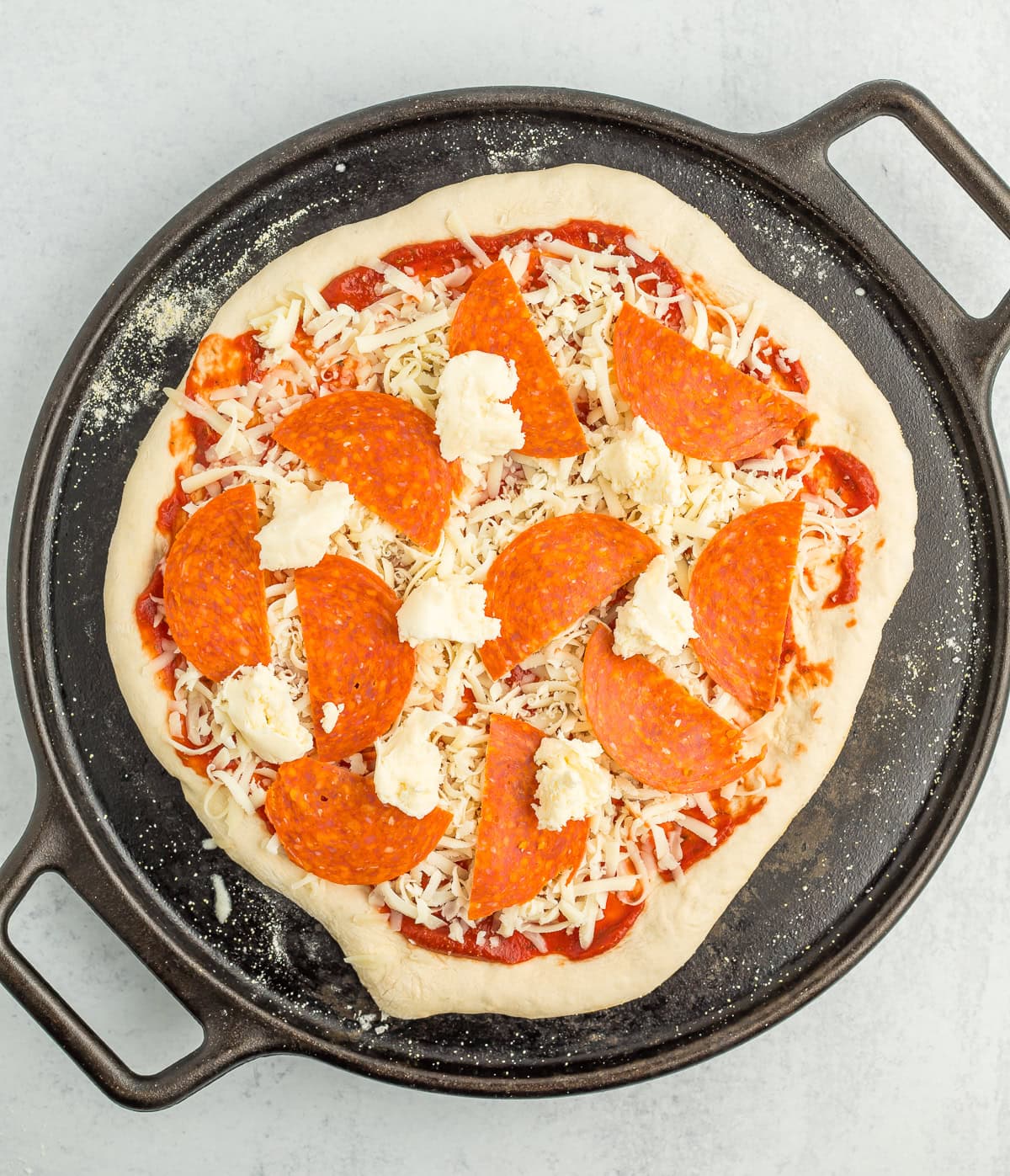 unbaked pizza on a cast iron sheet.