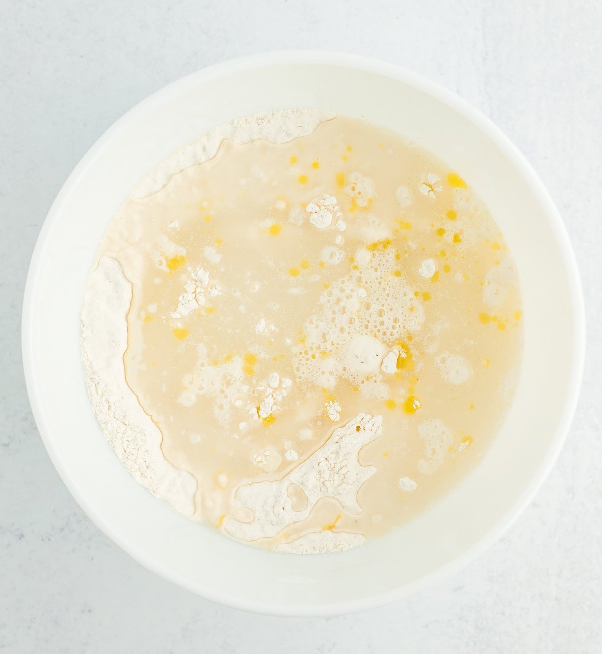 water, flour, and olive oil in a white bowl.