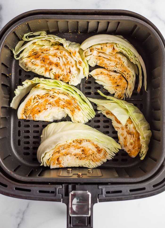 uncooked cabbage wedges in an air fryer basket.