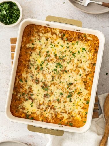 cheesy hamburger and rice casserole in a baking dish topped with chopped parsley.