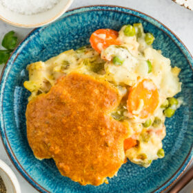 a serving of chicken pot pie casserole on a blue dish with herbs and salt.