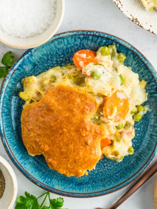 a serving of chicken pot pie casserole on a blue dish with herbs and salt.