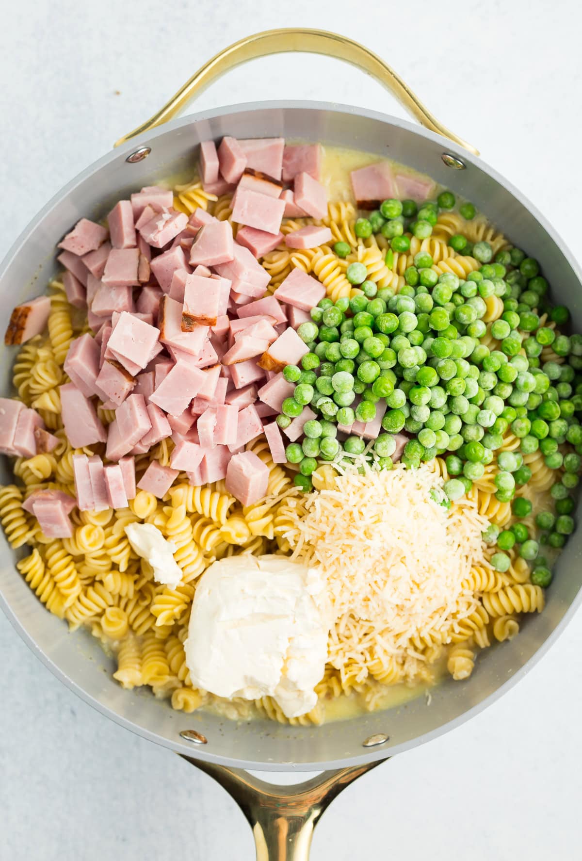 peas, chopped ham, Parmesan, rotini, and cream cheese in a skillet.
