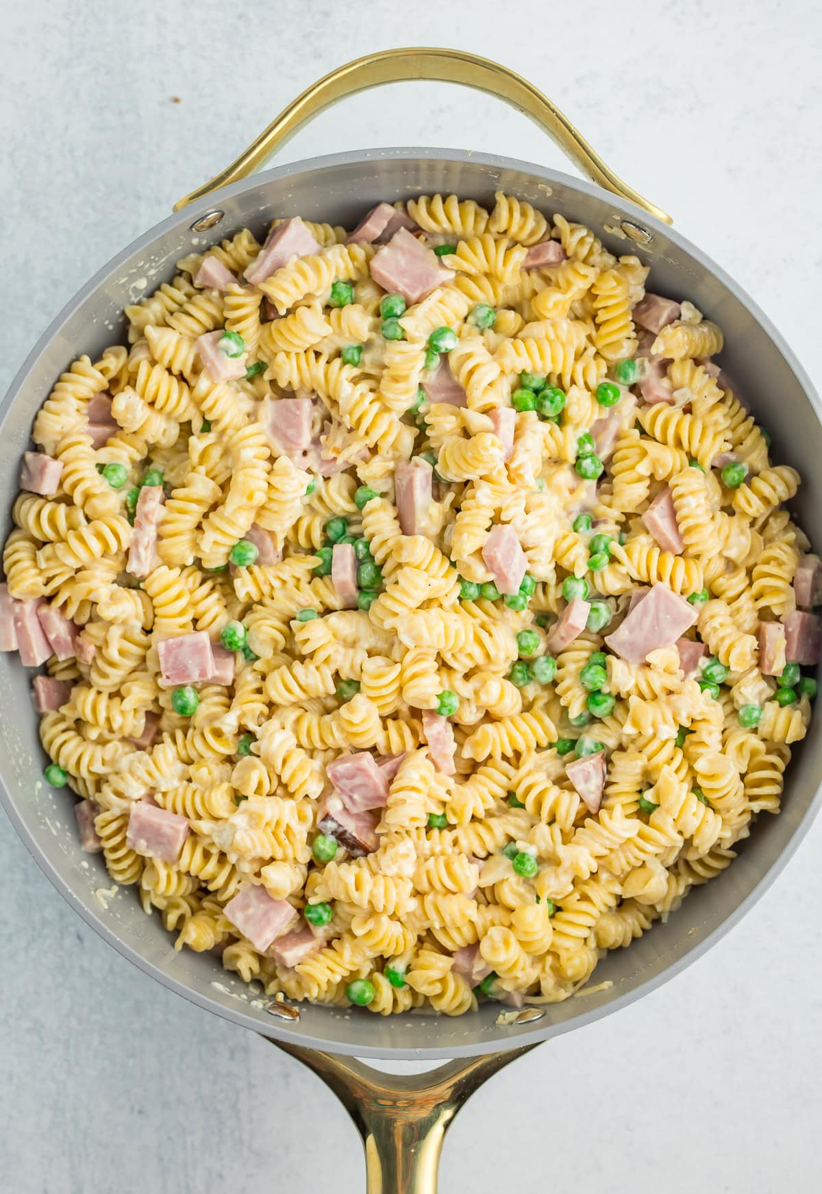 creamy pasta with peas and ham in a skillet.