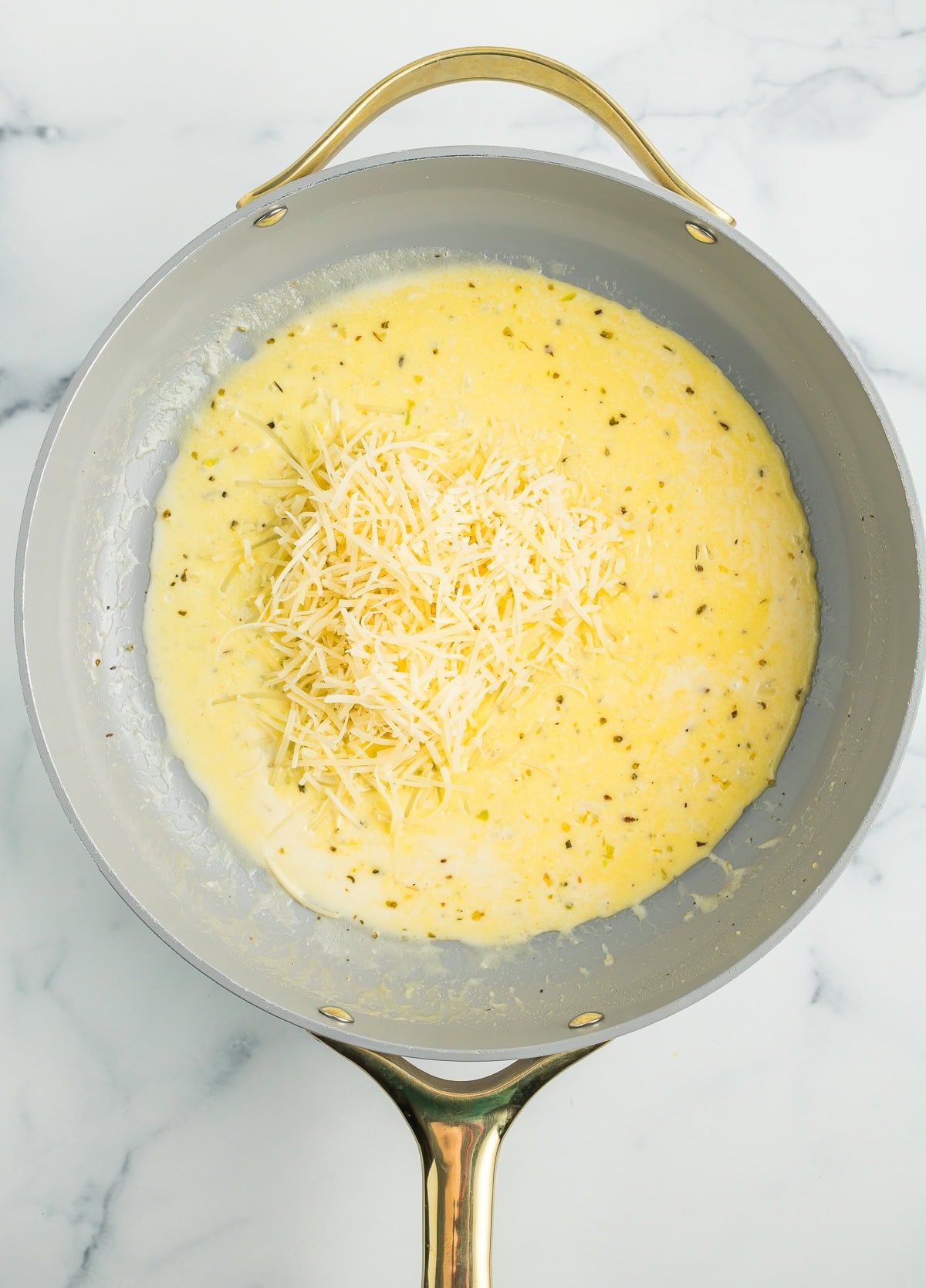 shredded Parmesan in a sauce in a skillet.