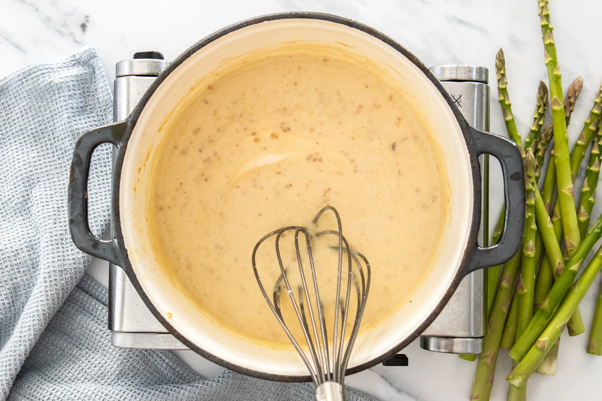 a whisk in a dutch oven making a cream sauce.