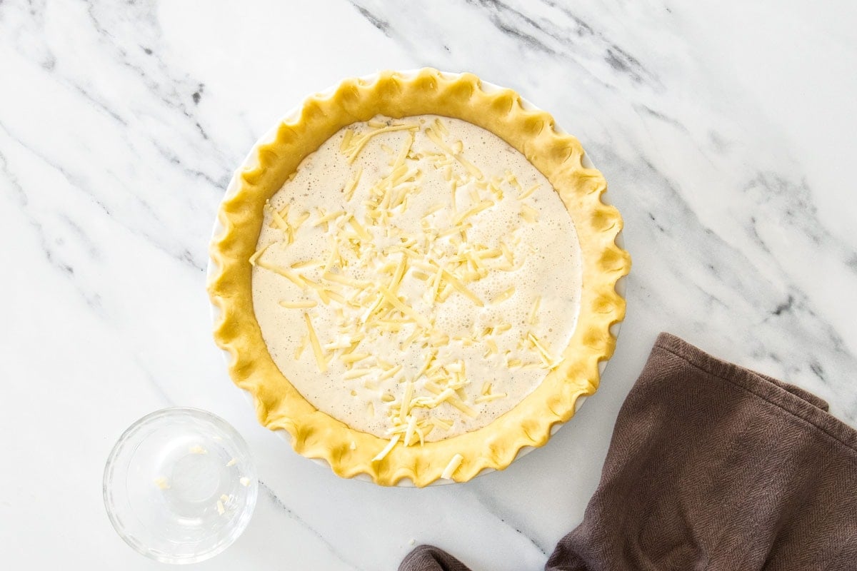 shredded cheddar sprinkled over whisked eggs and cream in an unbaked pie crust.