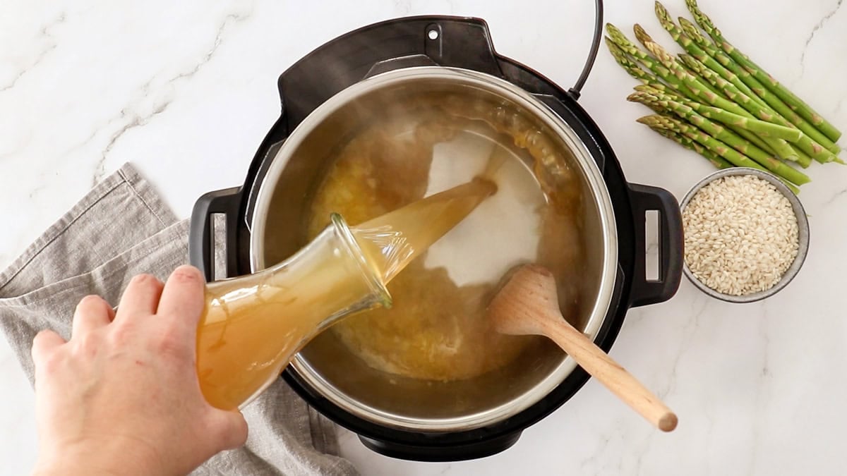 chicken stock being added to a pressure cooker.