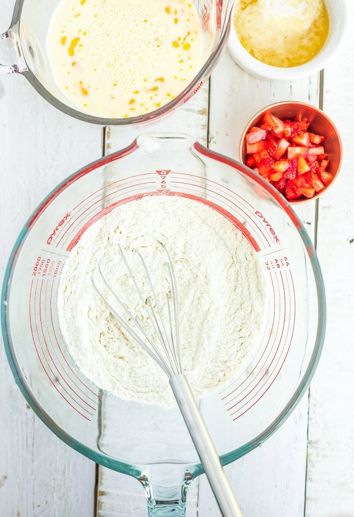 a whisk in a glass bowl with dry ingredients.