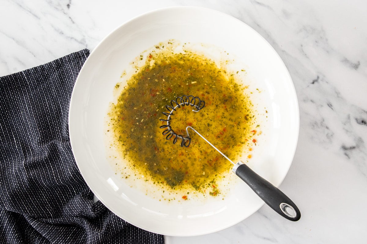 dressing and a whisk in a white bowl.