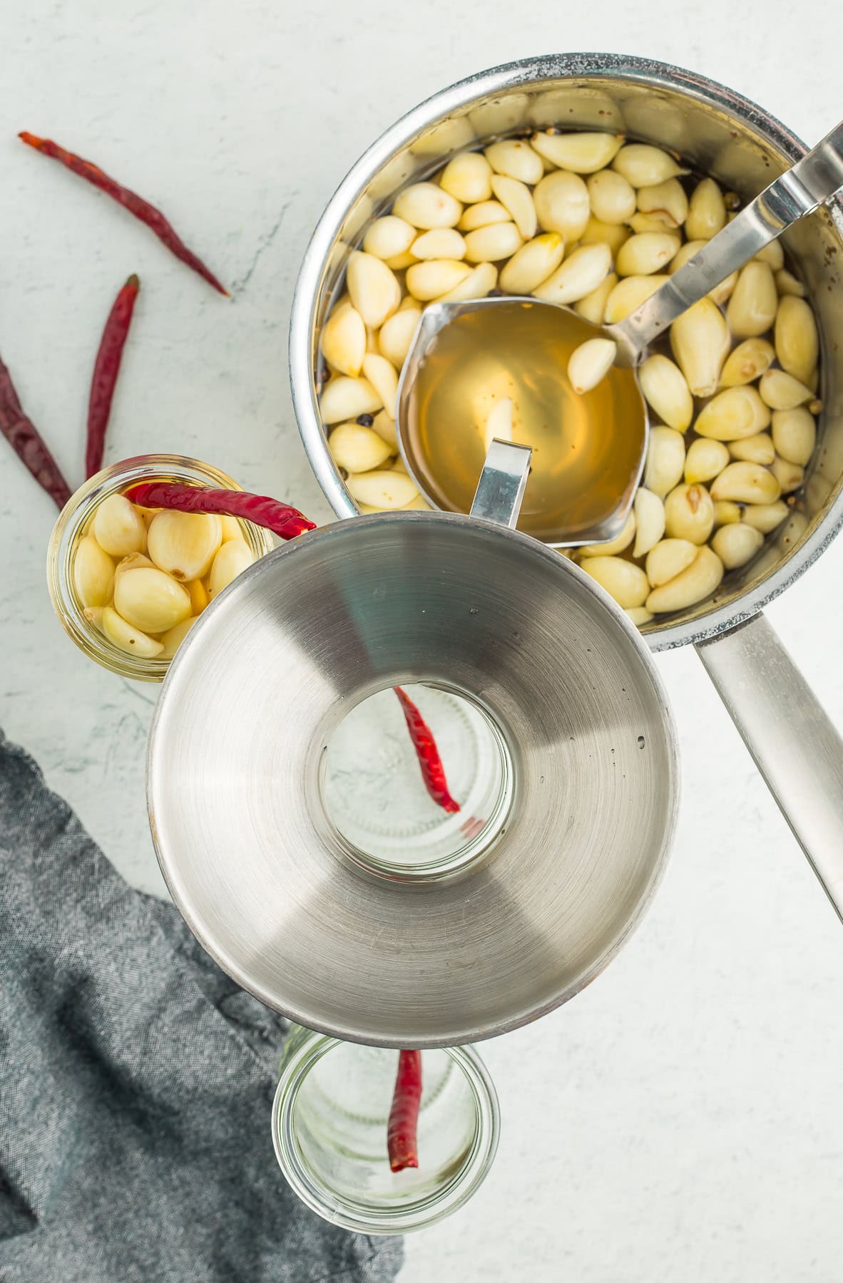 a canning funnel on jars with a saucepan and a ladle.