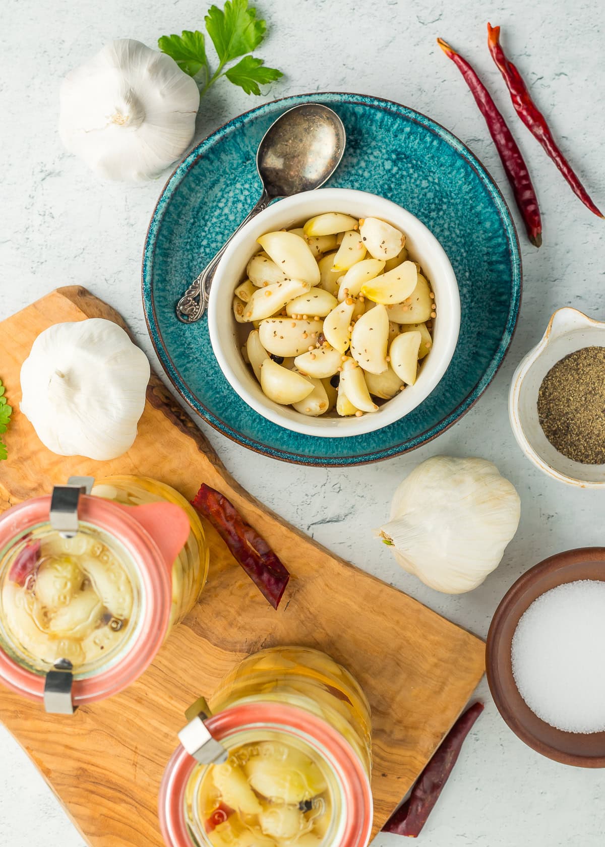 a white bowl of pickled garlic on a blue dish.